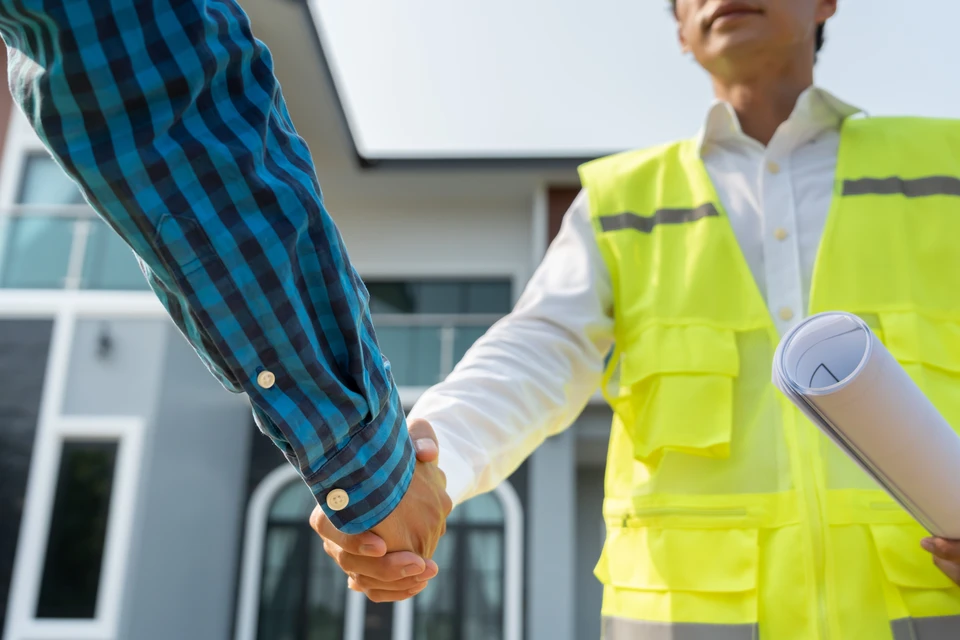 Professionnel en uniforme bleu devant pavillon résidentiel, tenant clipboard et stylo
